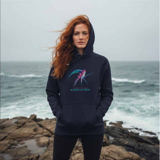 Woman wearing a French Navy Hoodie with the Blanket Octopus design standing on a rocky coastline