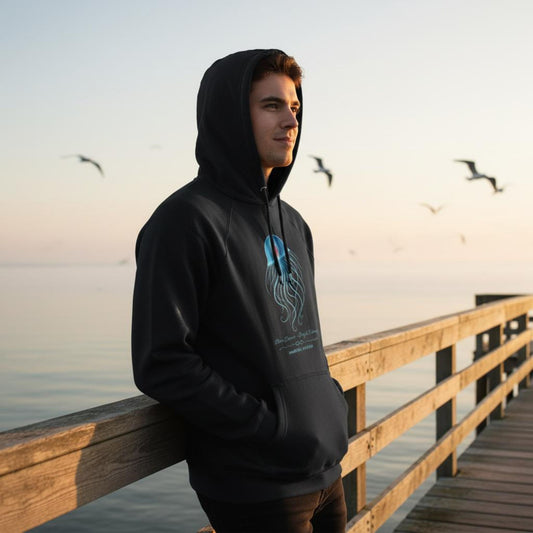 The organic unisex Hoodie with the Immortal Jellyfish design by seablub worn by a young man standing on a wooden pier with seagulls in the background
