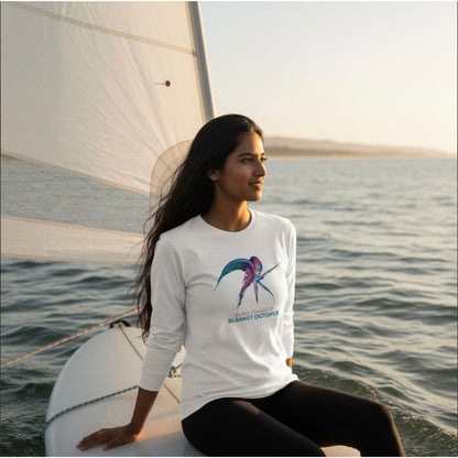 Model wearing a seablub unisex organic Long Sleeve Shirt with Blanket Octopus design in White sitting on a surfboard at sea